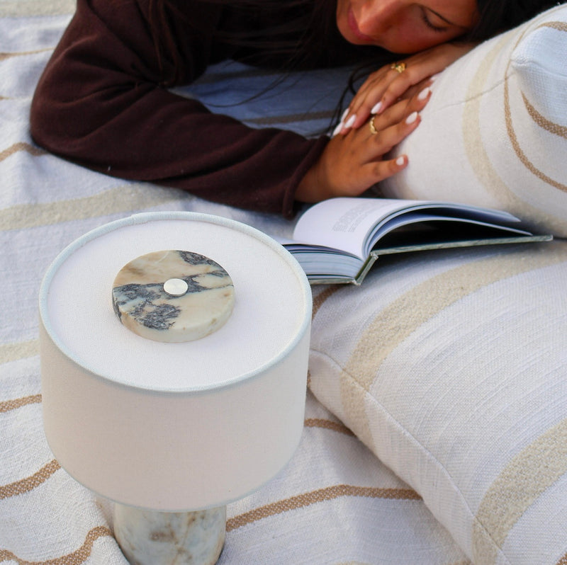 Calacatta Viola marble table lamp styled outside on blanket with warm ambient glow