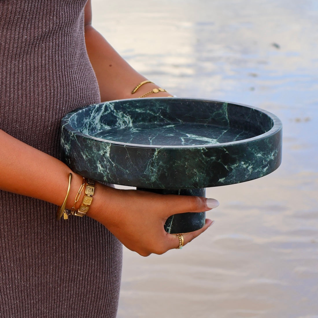 Verde Alpi marble pedestal bowl showing natural green stone veining held by woman
