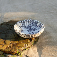 Calacatta Viola marble bowl showing natural marble veining on a beach rock 