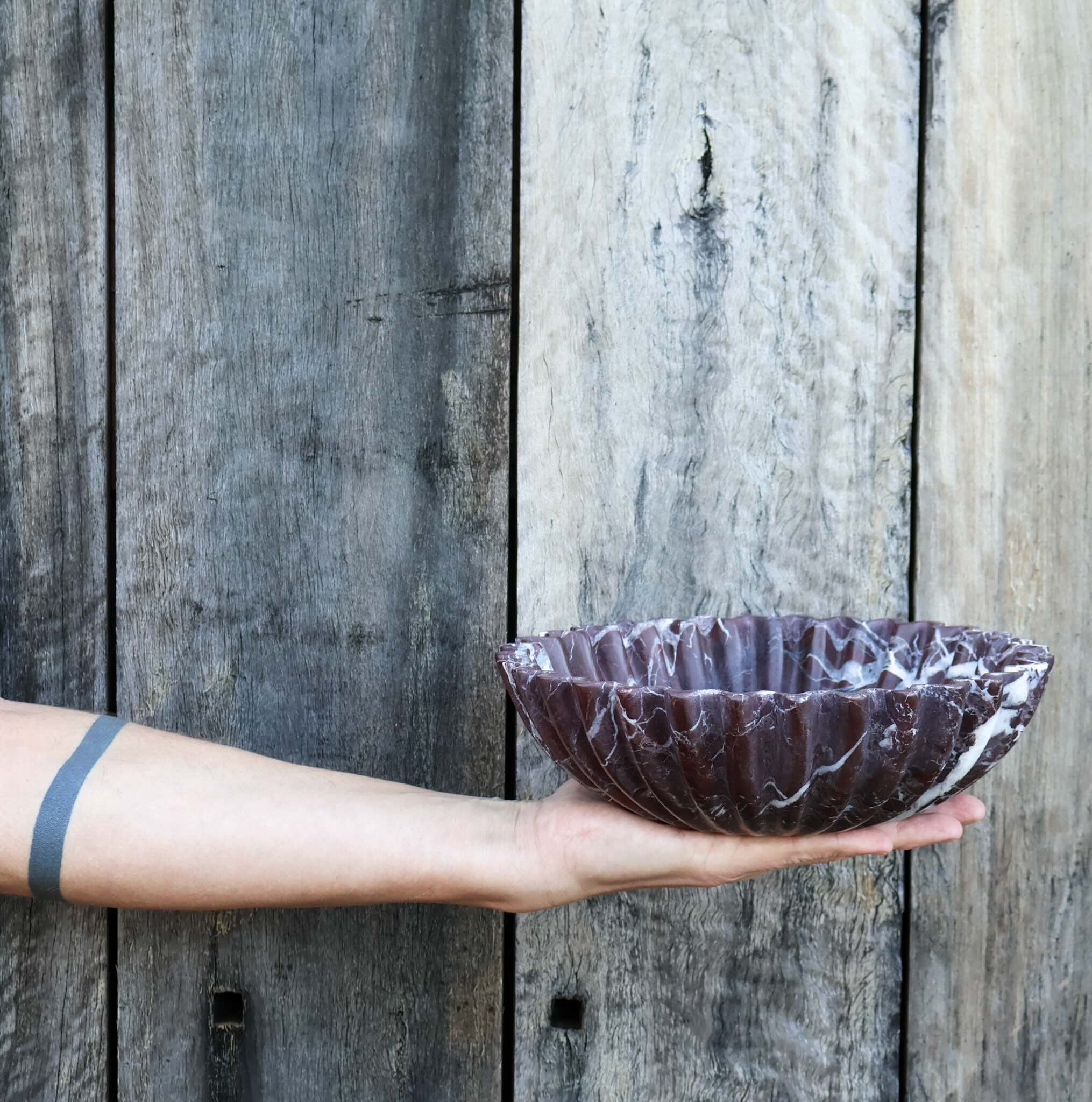 Rosso Levanto marble scalloped bowl sculptural red marble bowl by Lokah Co held by man