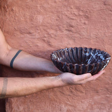 Scalloped edge Rosso Levanto marble bowl carved from natural stone held by man with tattooed arms