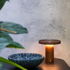 Modern walnut wood table lamp with smooth dimming dial next to a Verde Alpi marble bowl