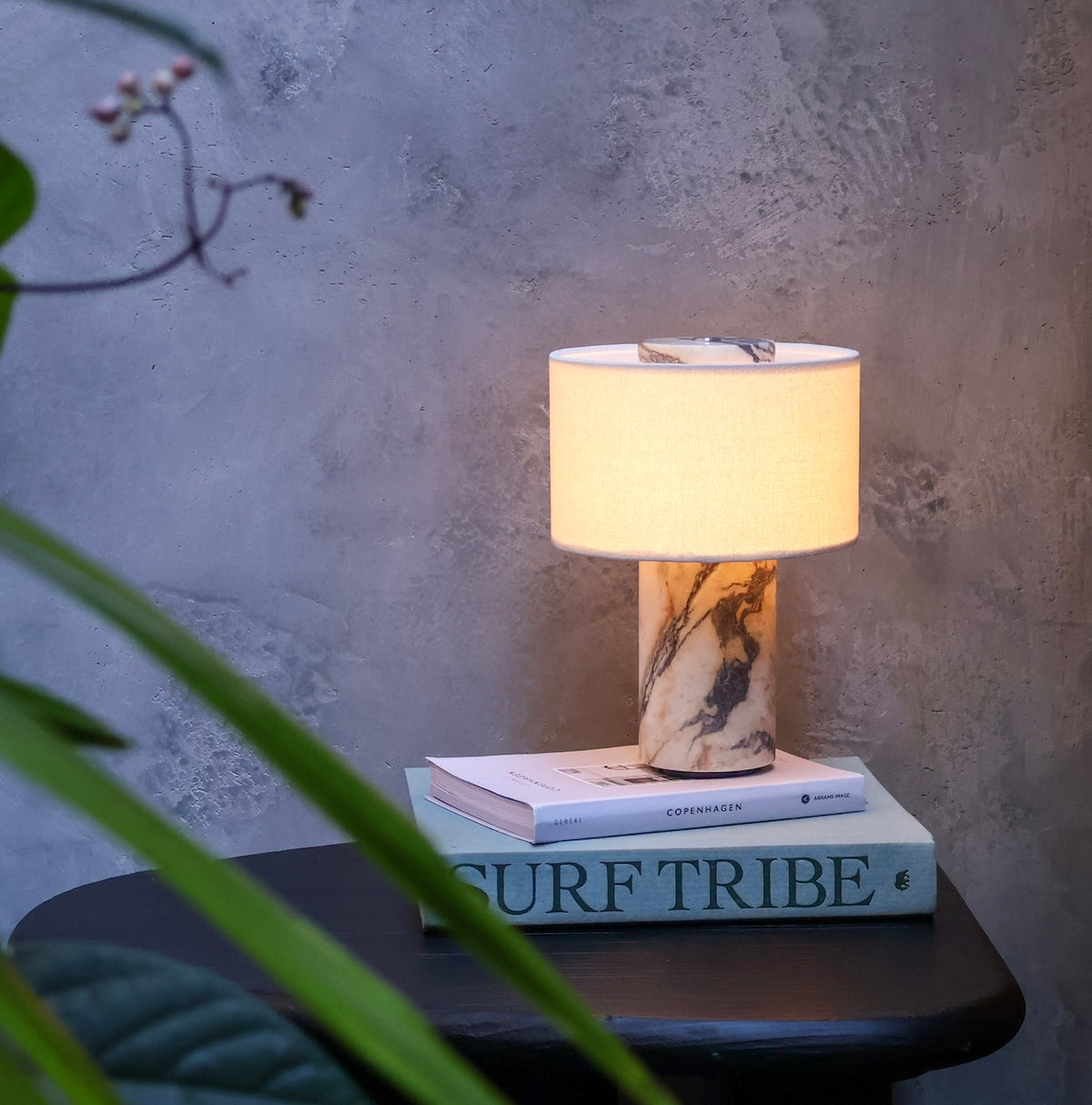 Illuminated cordless table lamp with a sculptural Calacatta Viola marble base, warm fabric shade and distinctive burgundy veining.