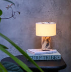 Illuminated cordless table lamp with a sculptural Calacatta Viola marble base, warm fabric shade and distinctive burgundy veining.